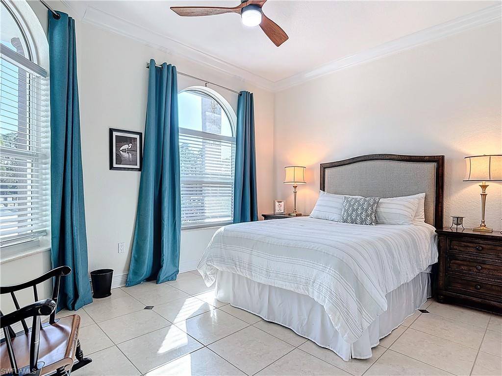 Split Bedroom with ornamental molding, light tile patterned flooring, and ceiling fan