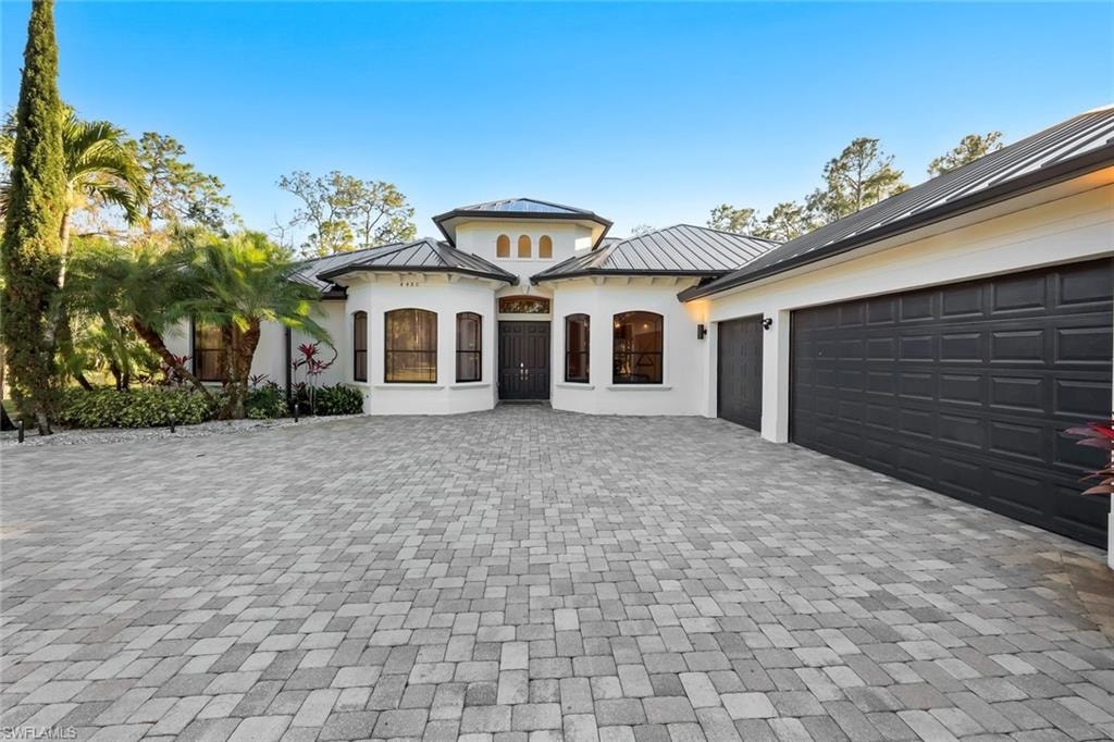 Mediterranean / spanish-style home featuring a standing seam roof, decorative driveway, stucco siding, and a garage