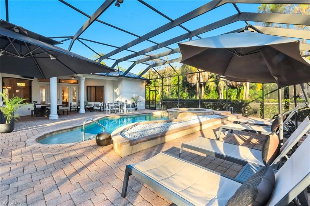Relaxing pool / spa with a patio area, glass enclosure, outdoor lounge area, and a sunroom