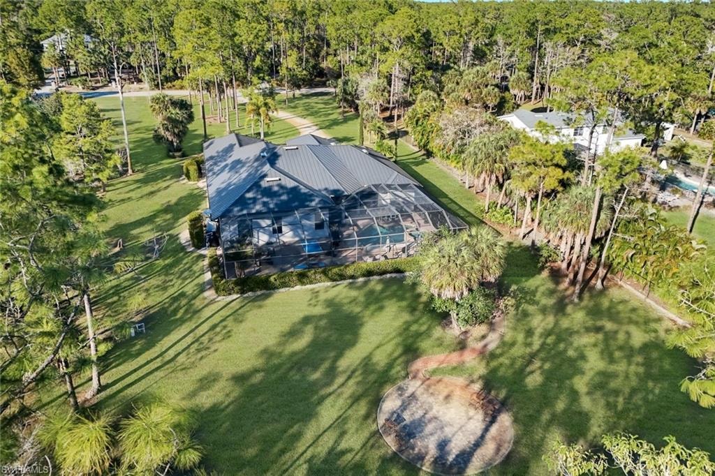 Aerial view of property and surrounding area featuring a tree filled landscape