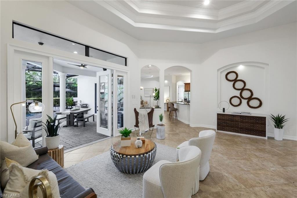 Living room with arched walkways, ornamental molding, and a high ceiling