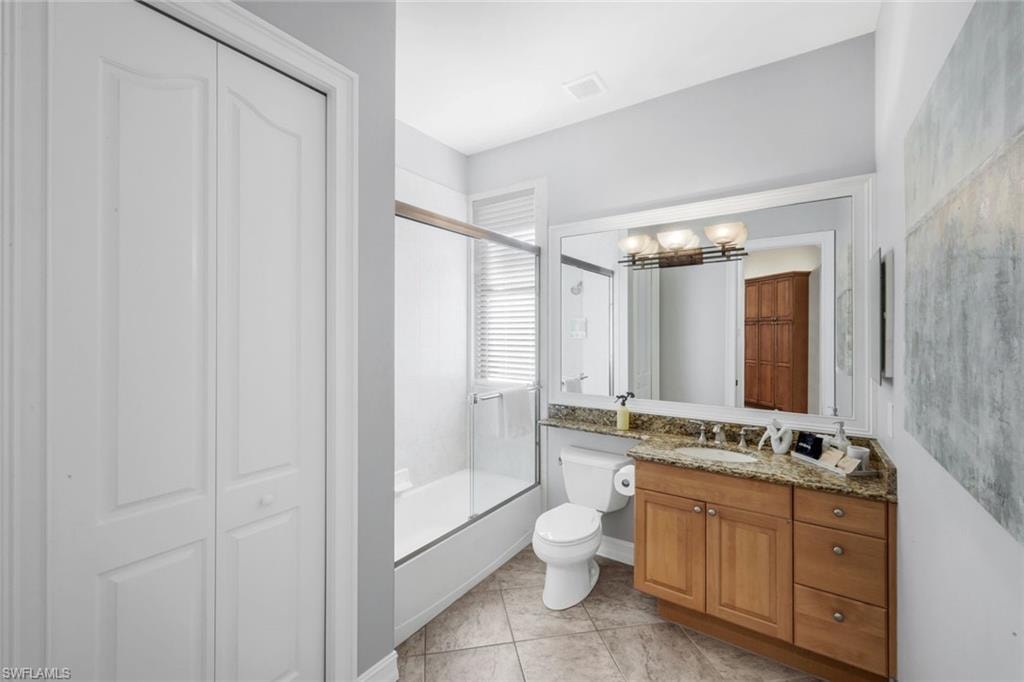 Full bath featuring a closet, vanity, combined bath / shower with glass door, and light tile patterned flooring
