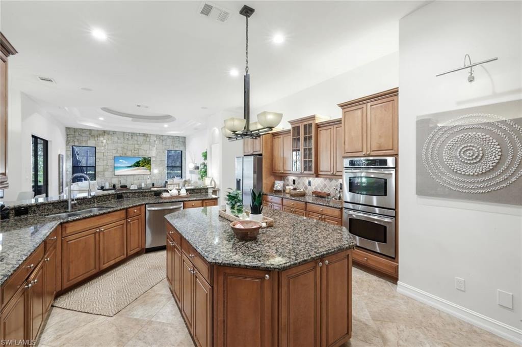 Kitchen featuring wood finish cabinetry, dark stone counters, stainless steel appliances, and a center island