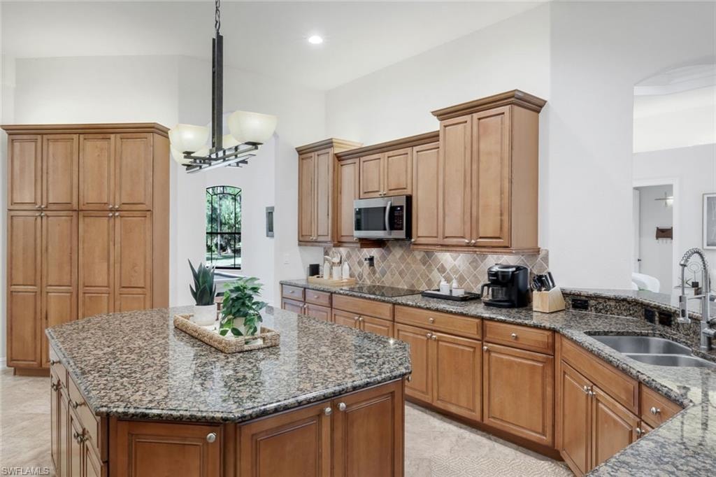 Kitchen featuring a kitchen island, dark stone counters, wood finish cabinetry, and decorative backsplash