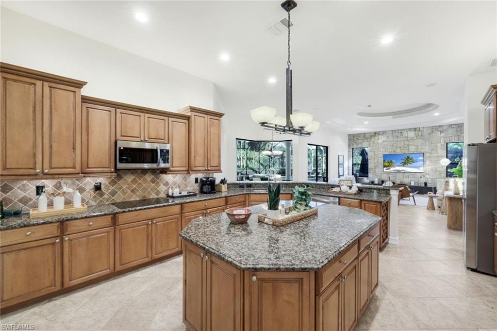 Kitchen featuring wood finish cabinets, dark stone counters, a center island, and stainless steel appliances