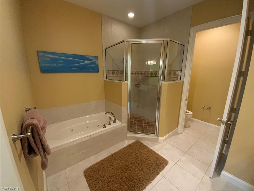 Bathroom featuring tile patterned flooring, a tub with jets, a stall shower, and recessed lighting