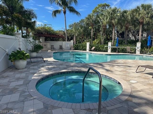 Community pool with a patio area and a hot tub