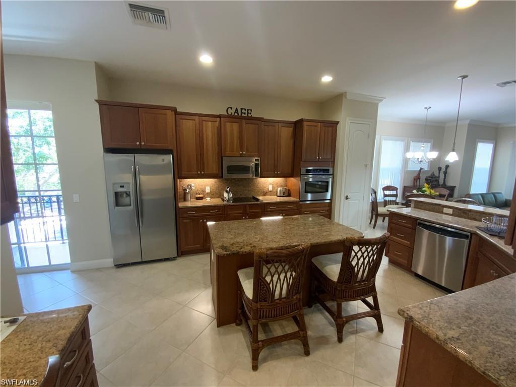 Kitchen featuring plenty of natural light, appliances with stainless steel finishes, a breakfast bar, light stone countertops, and recessed lighting