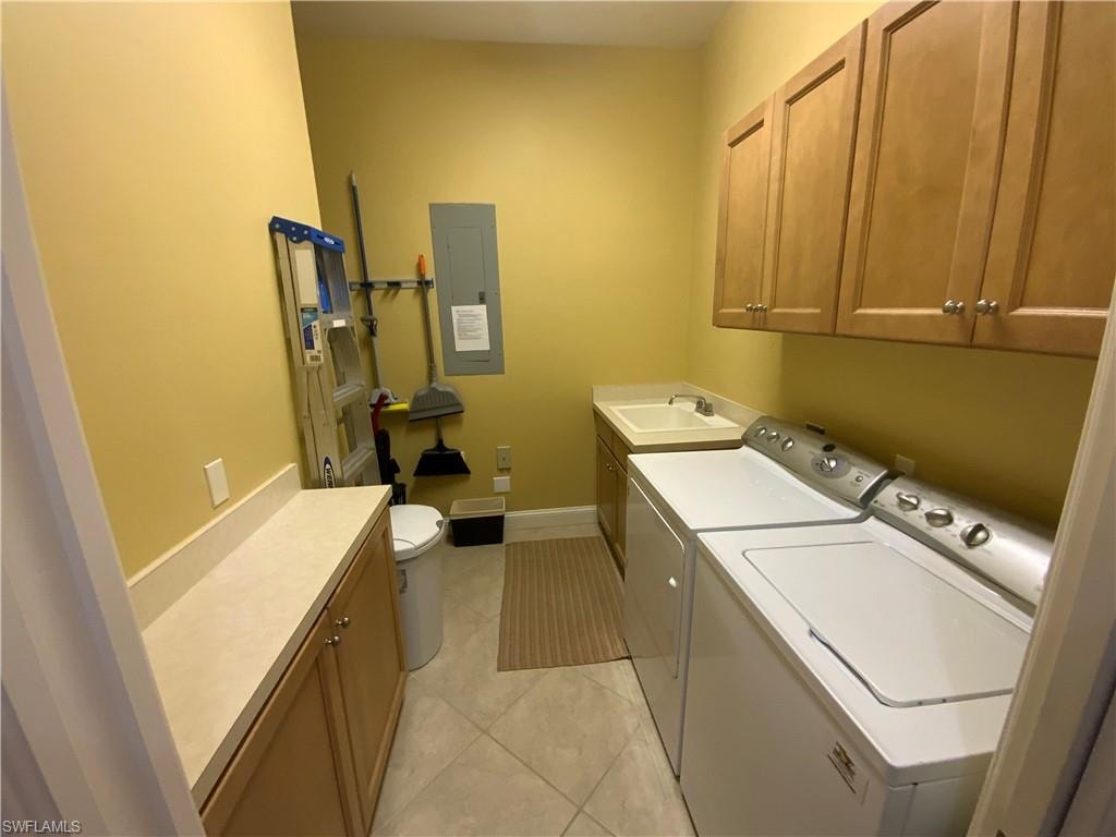 Laundry room with washing machine and clothes dryer, electric panel, cabinet space, and light tile patterned floors
