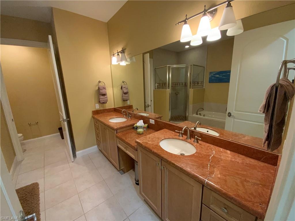 Bathroom featuring a bath, double vanity, a shower stall, and light tile patterned floors