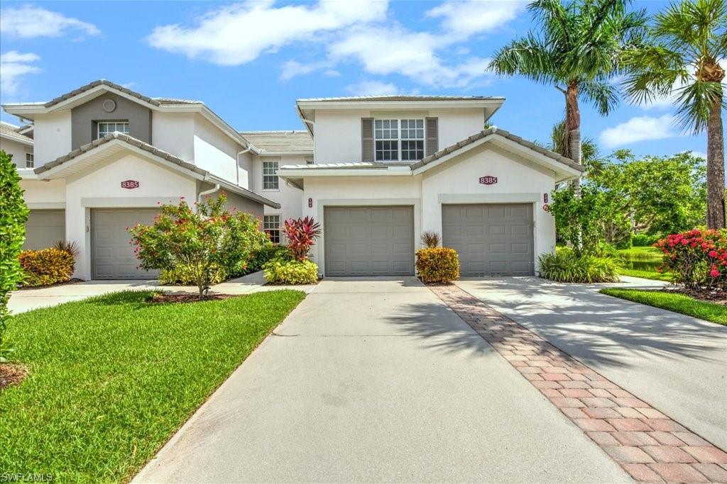 Traditional-style home with driveway, a garage, stucco siding, and a front lawn