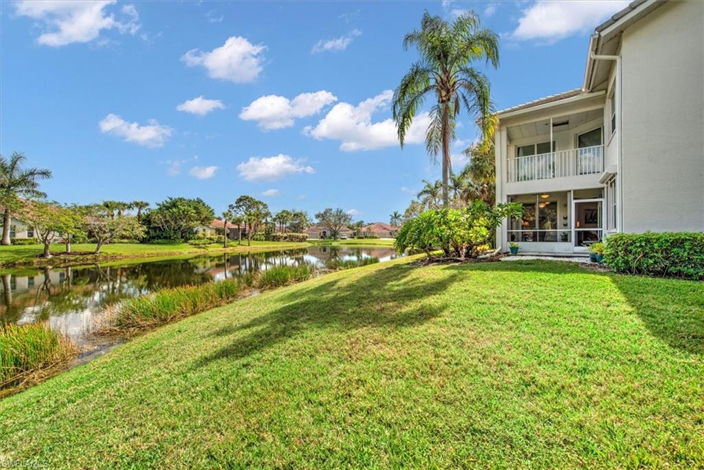 View of green lawn featuring a sunroom, a water view, and a balcony