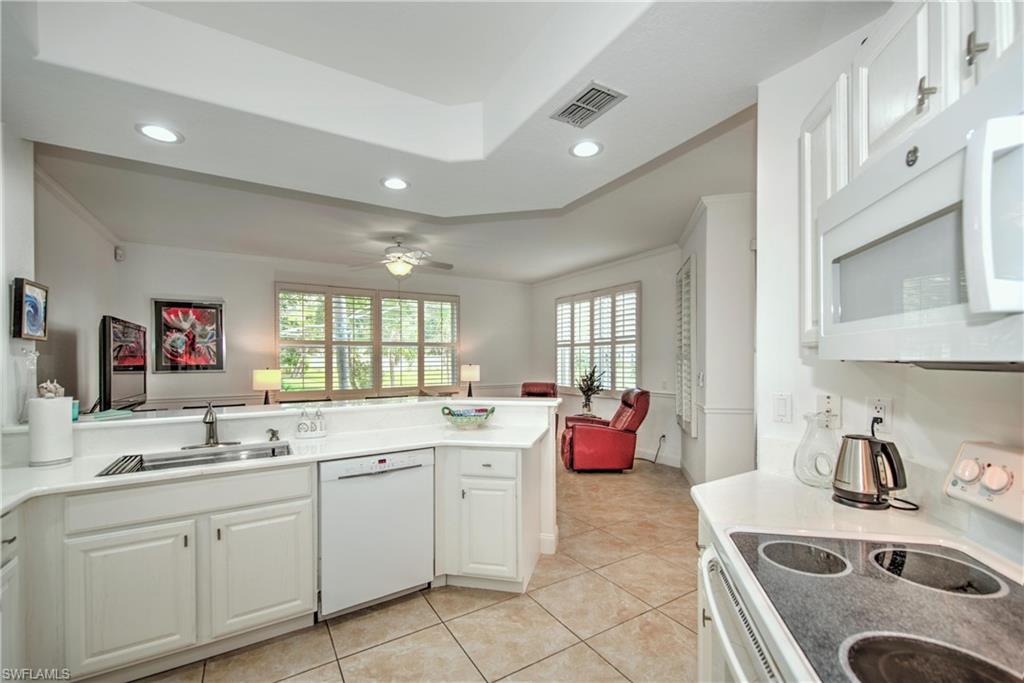 Kitchen with white appliances, white cabinets, open floor plan, light countertops, and light tile patterned floors