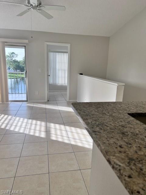 Unfurnished dining area with light tile patterned flooring, a textured ceiling, and ceiling fan