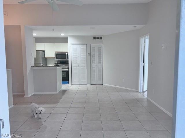 Kitchen featuring white cabinetry, stainless steel appliances, recessed lighting, light tile patterned floors, and a peninsula