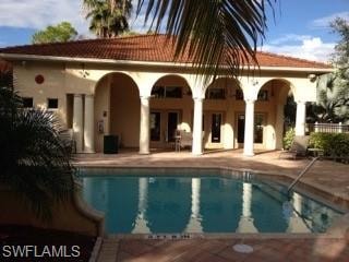 Back of property with a patio area, an outdoor pool, stucco siding, and a tiled roof