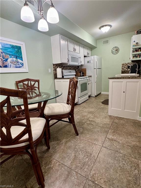 Kitchen featuring white cabinetry, backsplash, white appliances, and hanging light fixtures