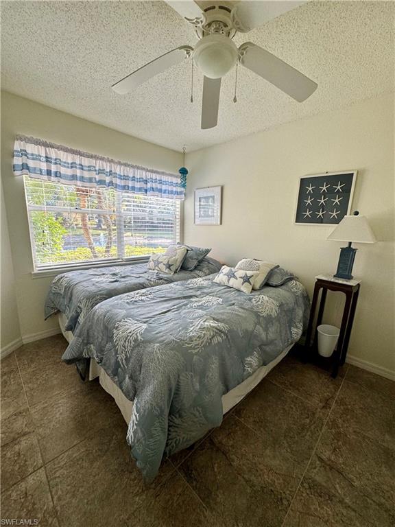 Bedroom with ceiling fan and a textured ceiling