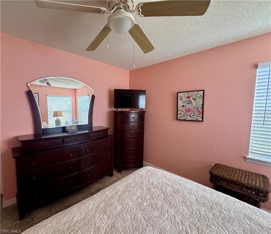 Bedroom with a textured ceiling and a ceiling fan