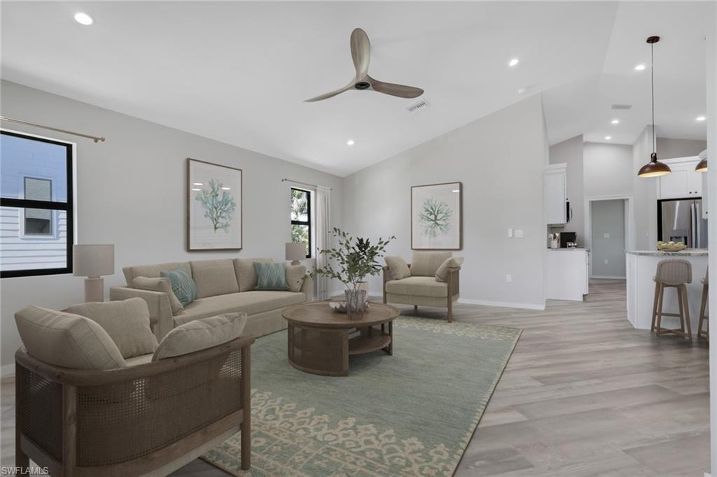 Living area with light wood-style flooring, a ceiling fan, recessed lighting, and high vaulted ceiling