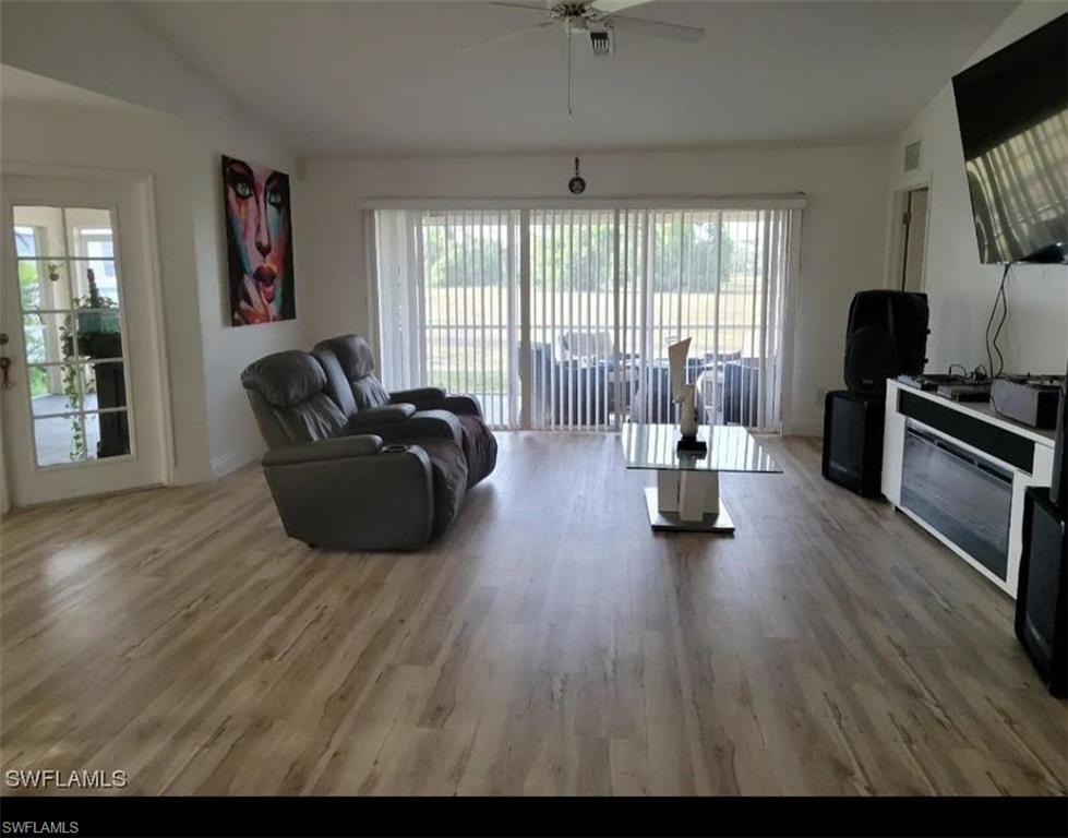 Living area with light wood-style flooring, plenty of natural light, ceiling fan, and vaulted ceiling