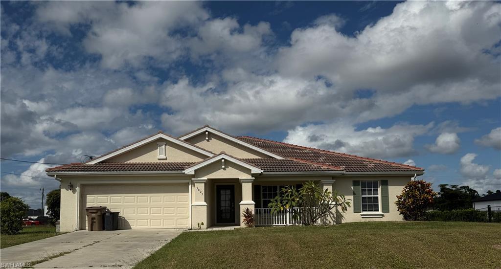 View of front of property with a tiled roof, stucco siding, a front lawn, concrete driveway, and a garage