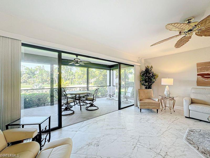 Living area featuring a ceiling fan, a sunroom, and marble look tiles