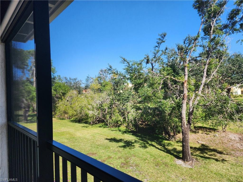 View of green lawn with a sunroom and a balcony