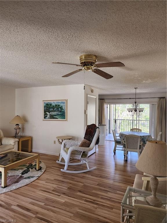 Living room featuring wood finished floors, ceiling fan, a chandelier, and a textured ceiling