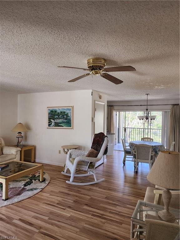 Living area with ceiling fan, wood finished floors, a textured ceiling, and a chandelier