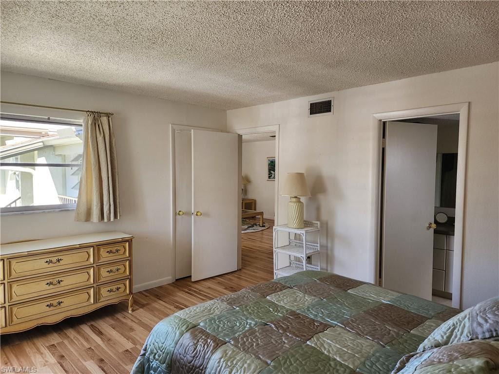Bedroom with light wood finished floors and a textured ceiling