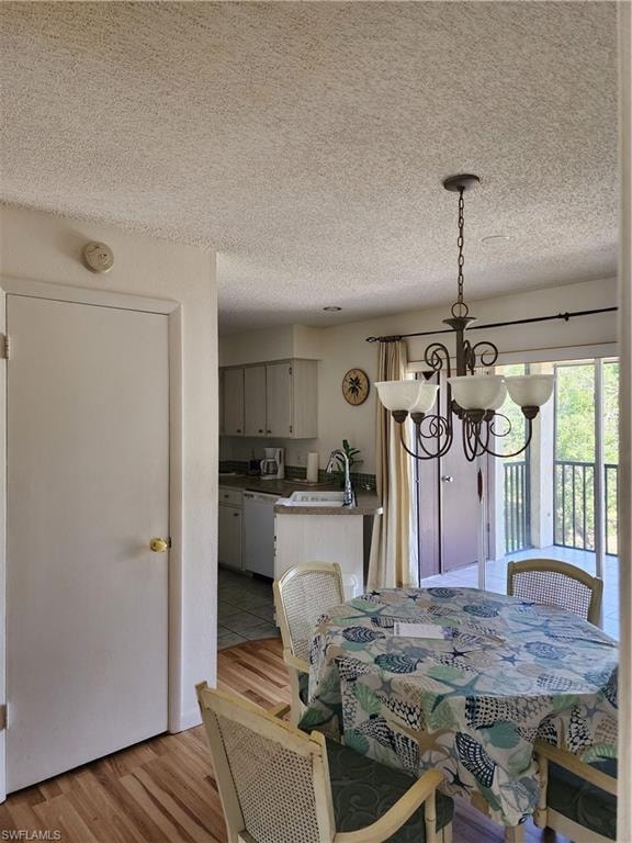 Dining room with light wood finished floors, a chandelier, and a textured ceiling