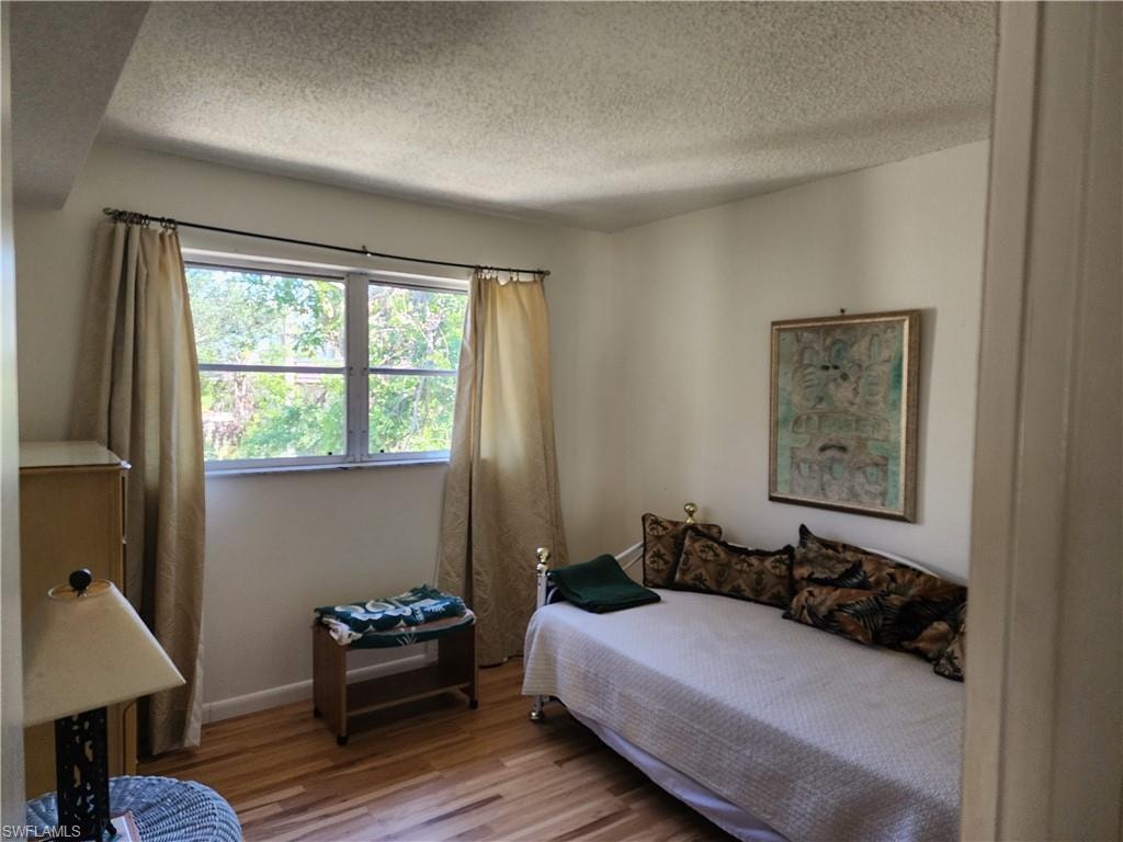 Bedroom with wood finished floors and a textured ceiling