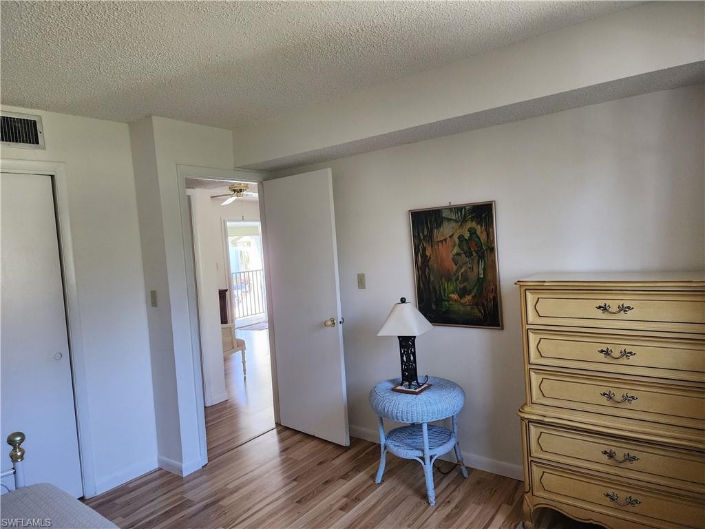 Sitting room featuring a textured ceiling, wood finished floors, and a ceiling fan