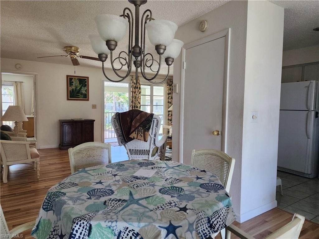 Dining area with a chandelier, a textured ceiling, wood finished floors, and ceiling fan
