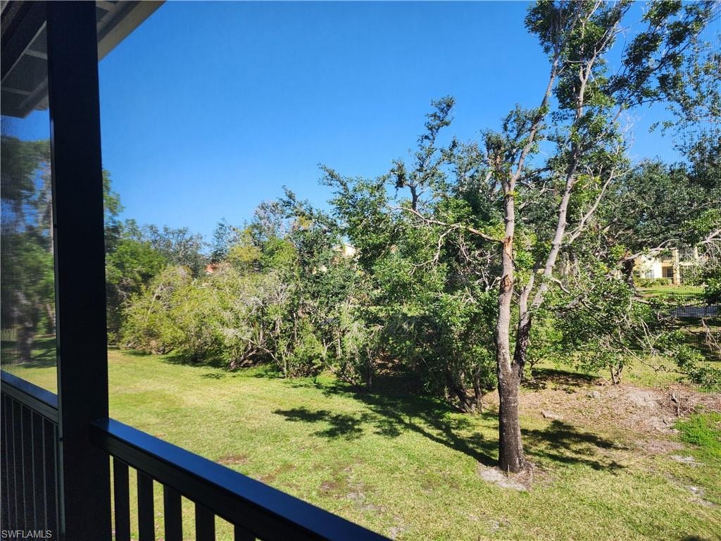 View of grassy yard featuring a balcony