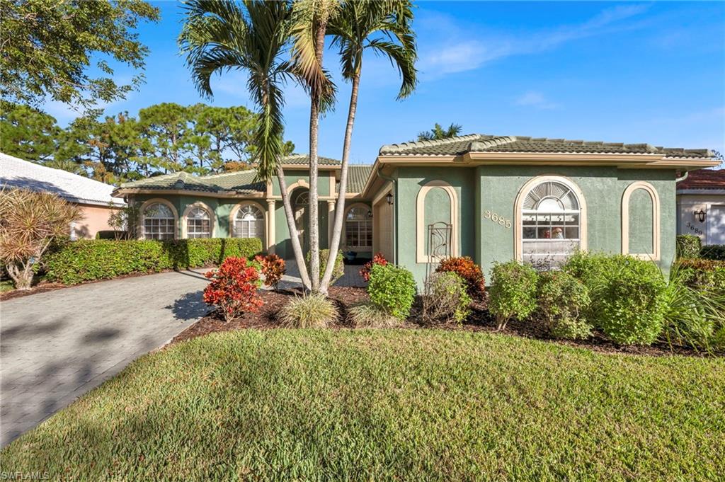 Ranch style home with stucco siding, a front yard, a tile roof, and driveway