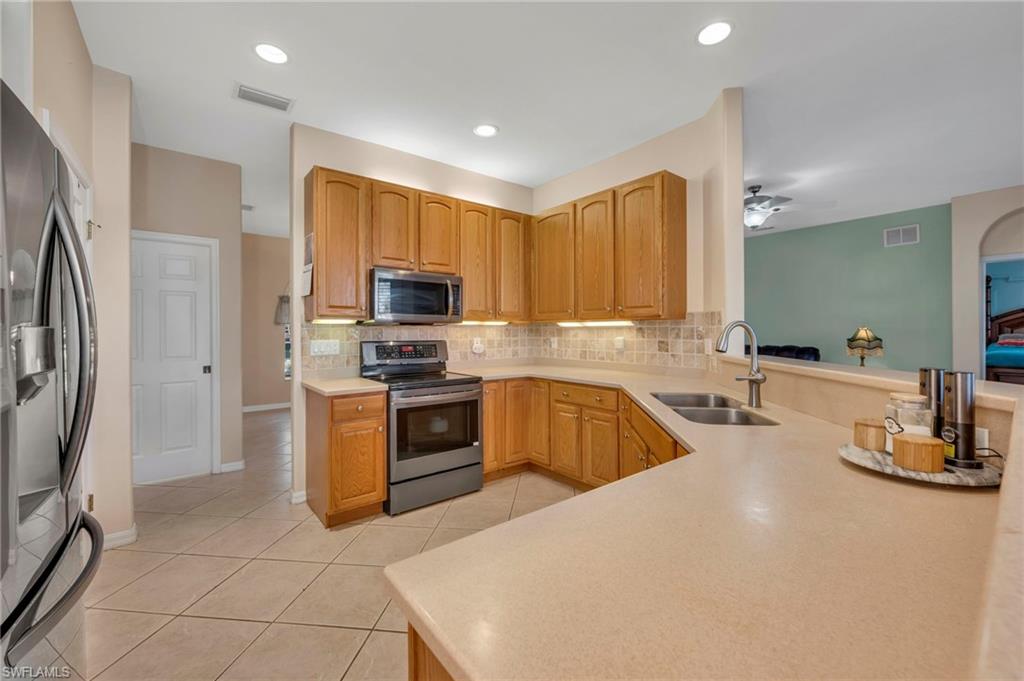 Kitchen with appliances with stainless steel finishes, light tile patterned floors, decorative backsplash, ceiling fan, and recessed lighting