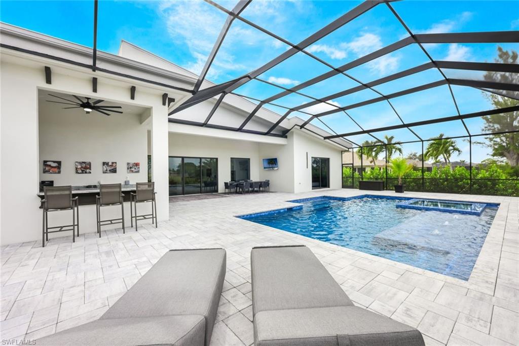 View of pool featuring glass enclosure, a patio area, a sunroom, and a ceiling fan