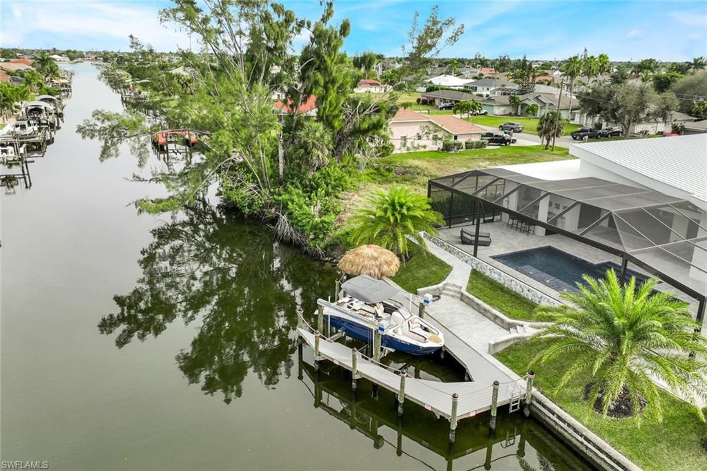 Dock area with boat lift, a water view, a lanai, a pool, and a residential view