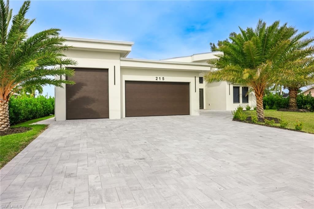View of front facade featuring a garage, decorative driveway, and stucco siding