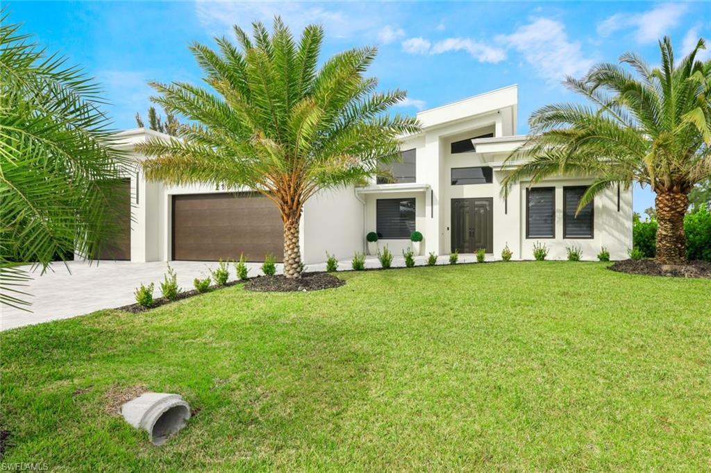 Modern home featuring driveway, a front yard, stucco siding, and a garage