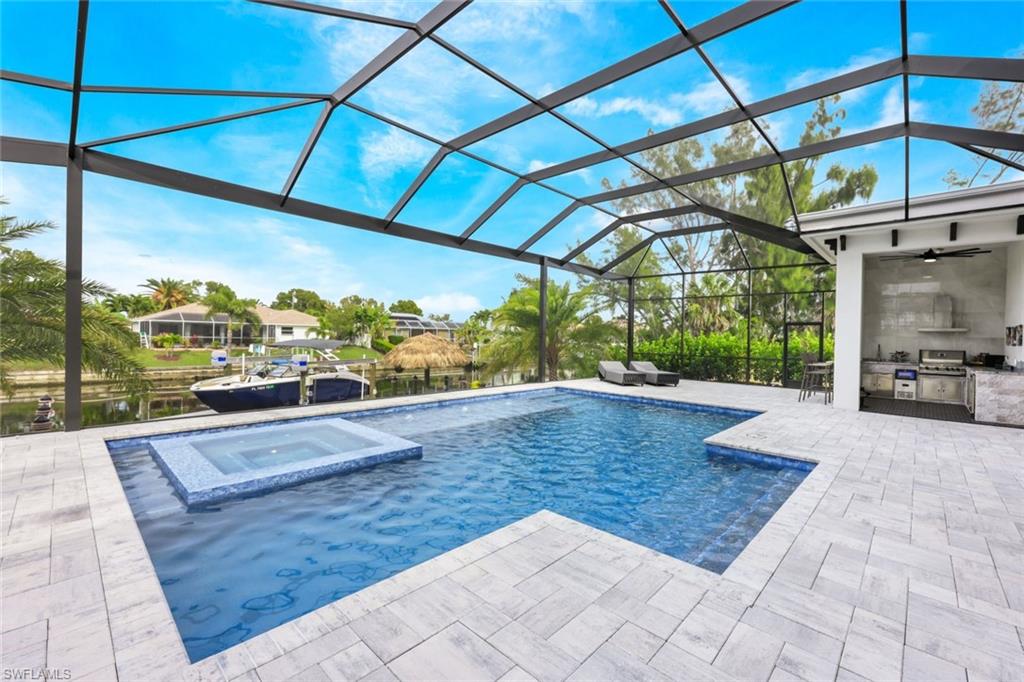 View of swimming pool with exterior kitchen, a water view, a lanai, a sunroom, and a patio area