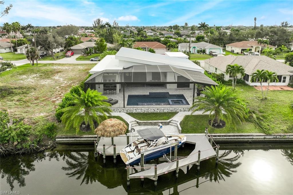 Dock with a residential view, an outdoor pool, glass enclosure, boat lift, and a water view