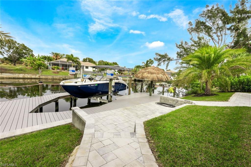 Dock featuring boat lift, a water view, and a lawn