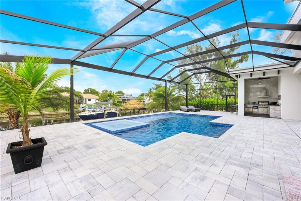 View of pool with area for grilling, glass enclosure, a patio, and a sunroom