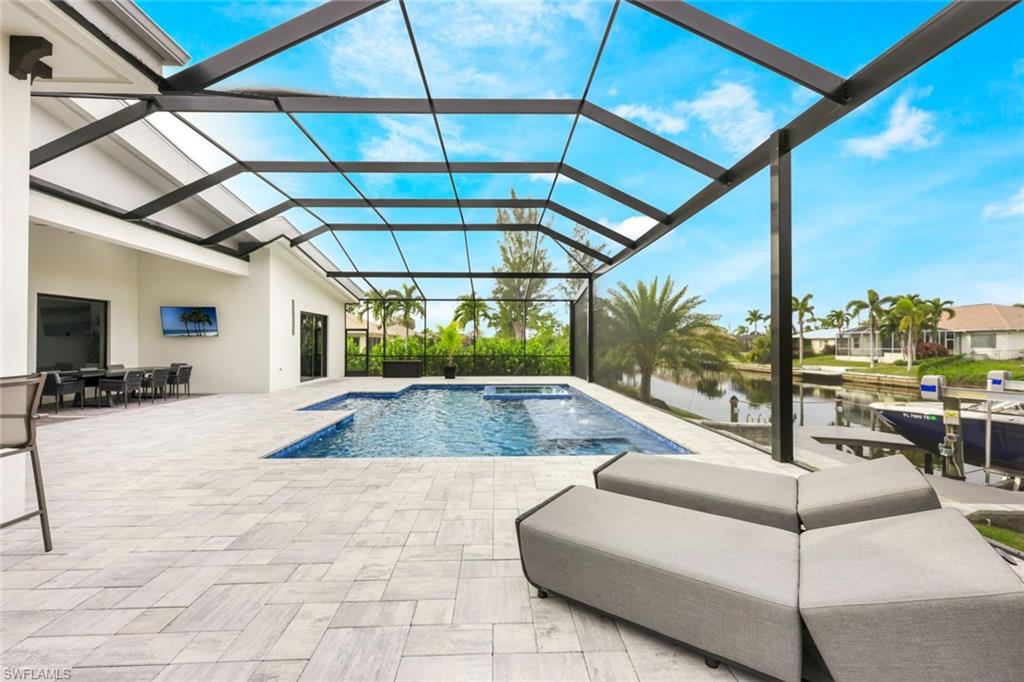 View of pool with a patio, a water view, a sunroom, glass enclosure, and a pool with connected hot tub