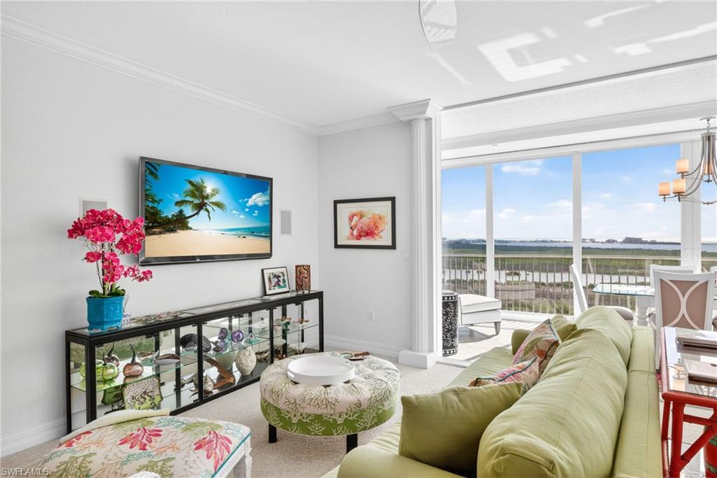 Living area featuring carpet floors, a chandelier, and crown molding