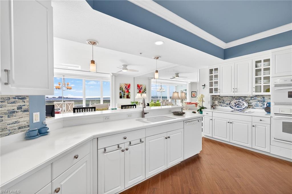 Kitchen featuring decorative backsplash, white cabinets, glass insert cabinets, pendant lighting, and crown molding