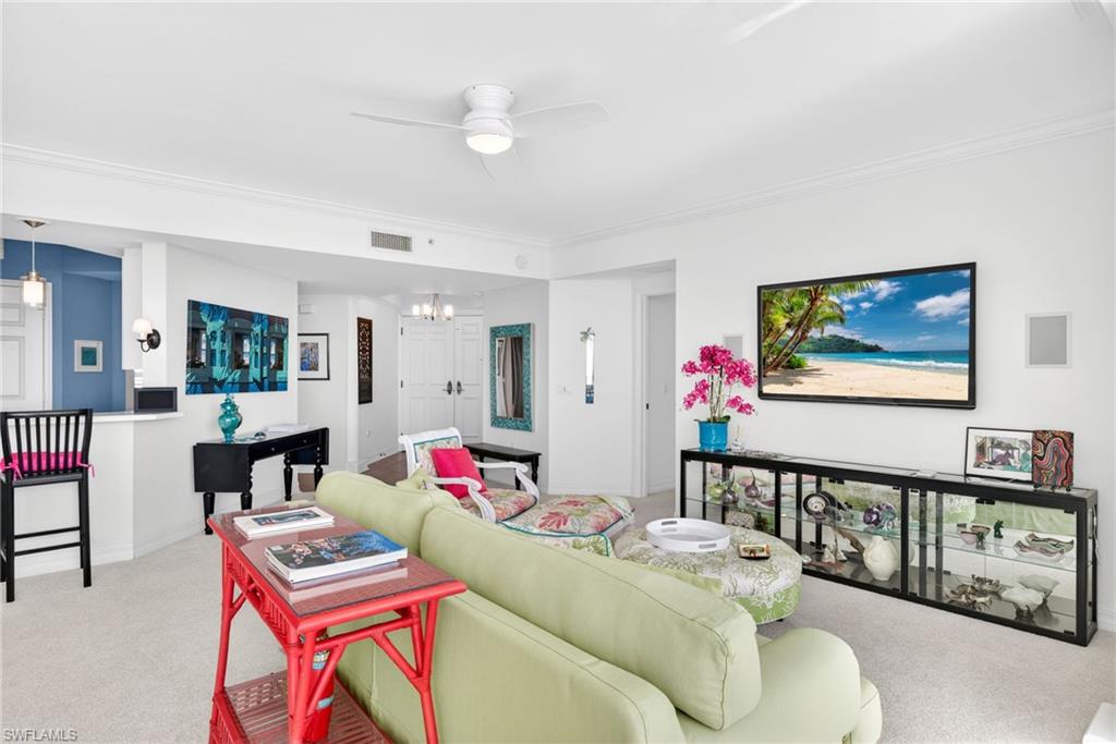 Living room featuring carpet floors, ceiling fan, ornamental molding, and a chandelier